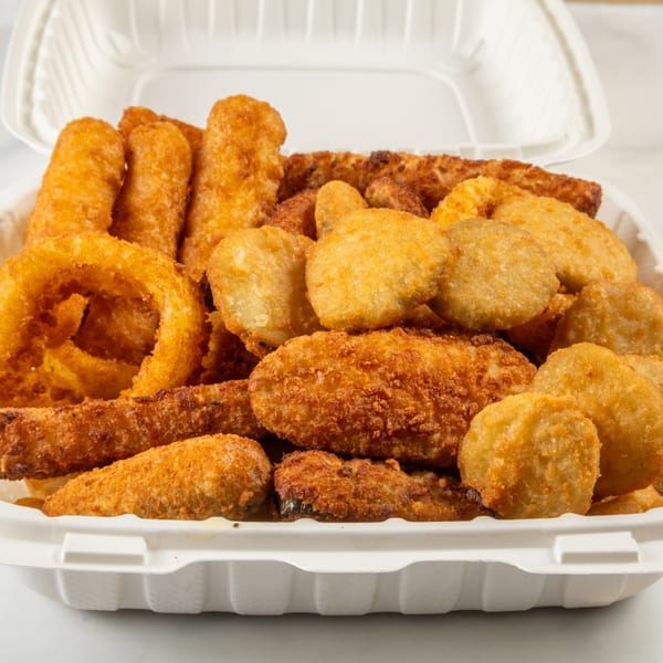 A white takeout container filled with golden-brown fried appetizers, including onion rings, mozzarella sticks, and mushrooms.