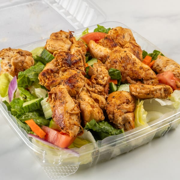 Grilled chicken salad with lettuce, tomatoes, cucumbers, and red onion in a plastic takeout container.